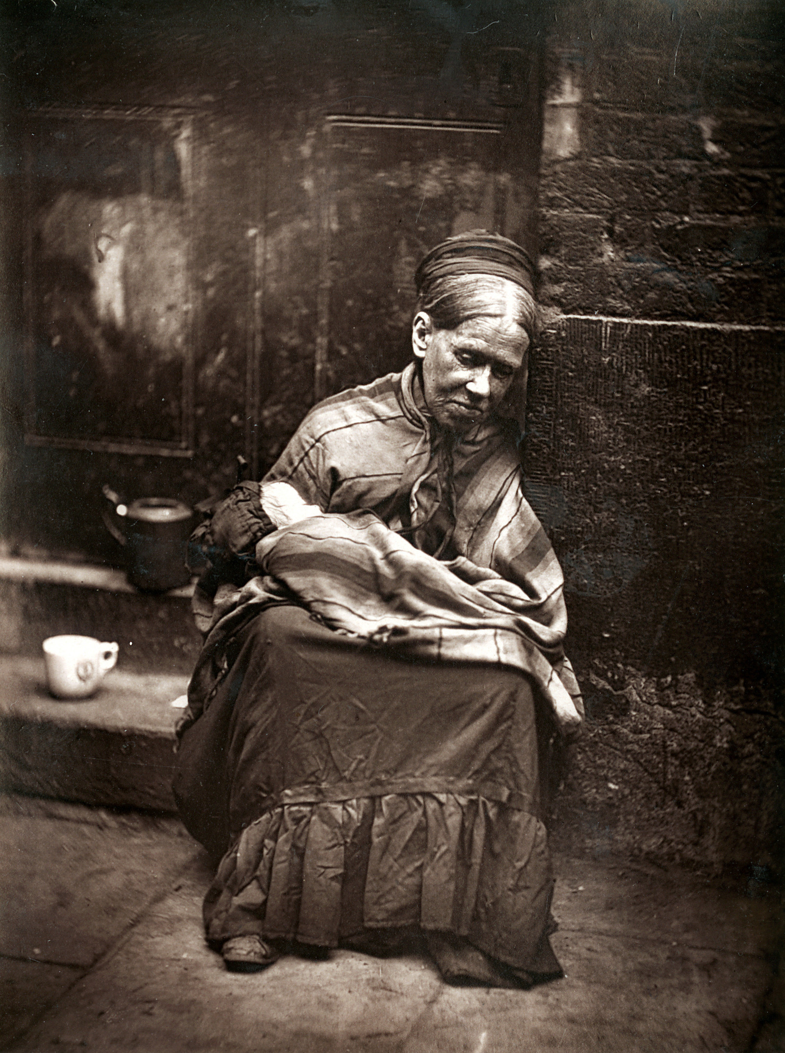 An old woman sits in a doorway, from 'Street Life in London' by John Thomson and Adolphe Smith, 1877. LSE Library. Public Domain.