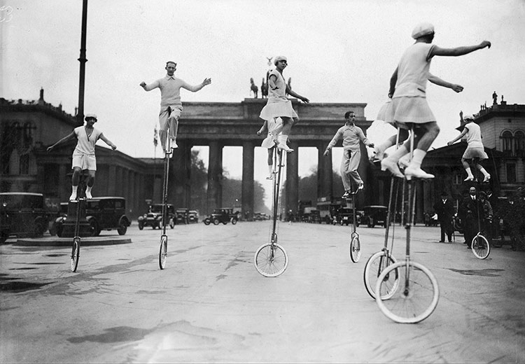 Unicyclists on Pariser Platz in front of the Brandenburg Gate, Berlin, c.1920.