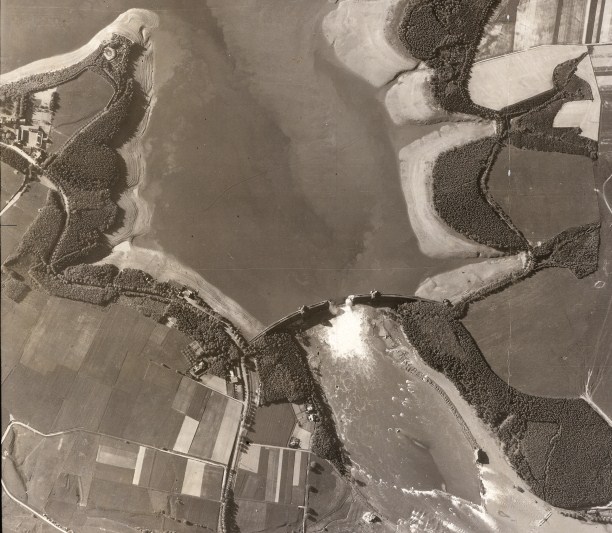 One of the most famous aerial photographs of the Second World War was taken from 30,000 feet on May 17th, 1943, only hours after the Dam Busters raid. The water from the reservoir is stil gushing through the 200-foot breech in the Mohne Dam. Mudflats appear as the water level drops above the dam. Photo / Trustees of the Medmenham Collection