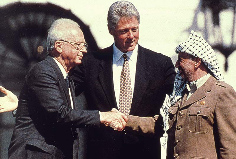 President Bill Clinton watches Yitzhak Rabin and Yasser Arafat shake hands in the garden of the White House, 13 September 1993.