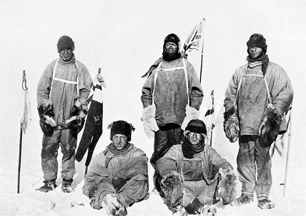 Photograph of the party taken January 17th, 1912, the day after they discovered Amundsen had reached the South Pole first. Left to right: Oates (standing), Bowers (sitting), Scott (standing in front of Union Jack flag on pole), Wilson (sitting), Evans (standing). Bowers took this photograph, using a piece of string to operate the camera shutter.