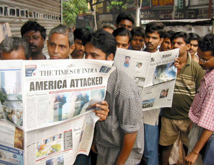 Passengers waiting at a bus-stop read details of the terrorists attacks on Washington and New York in newspapers in the eastern Indian city of Calcutta on September 12, 2001