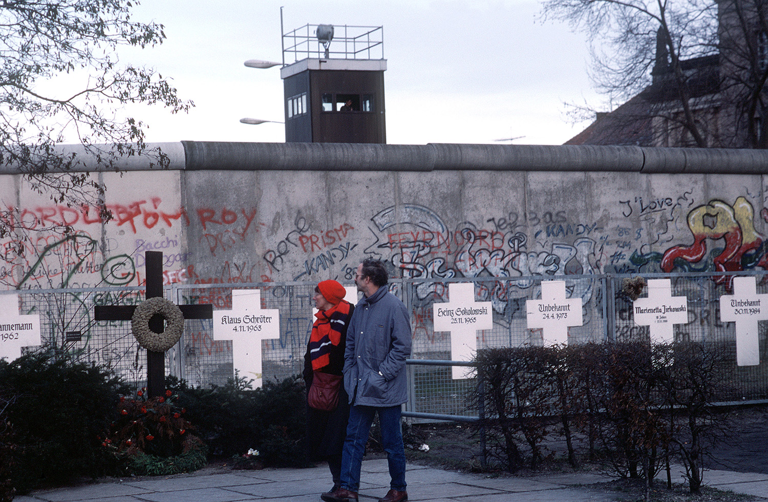 A couple reads grave markers of East Germans who died trying to escape East Germany across the Berlin Wall, 1990.