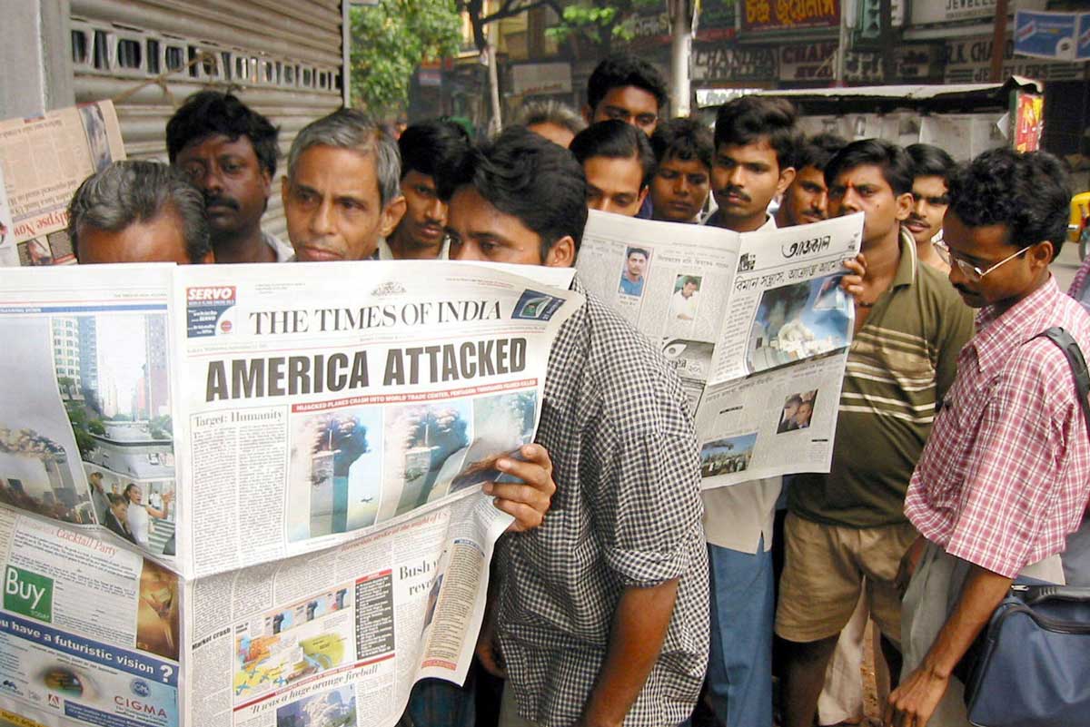 Passengers waiting at a bus-stop read details of the terrorists attacks on Washington and New York in newspapers in the eastern Indian city of Calcutta on September 12, 2001. Alamy/REUTERS/Jayanta Shaw JS/PB.