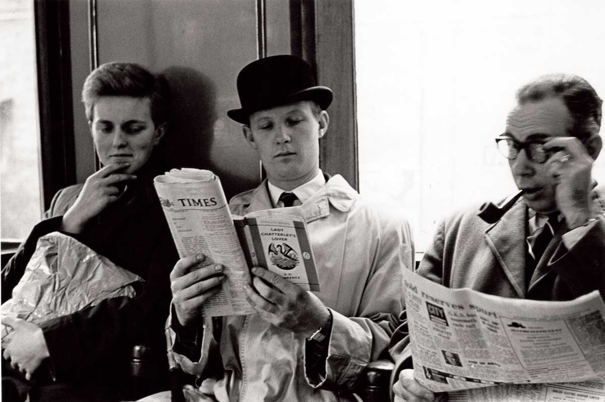 A commuter reads Lady Chatterley’s Lover over their neighbour’s shoulder, London Underground, 1960 © Hulton Getty Images.