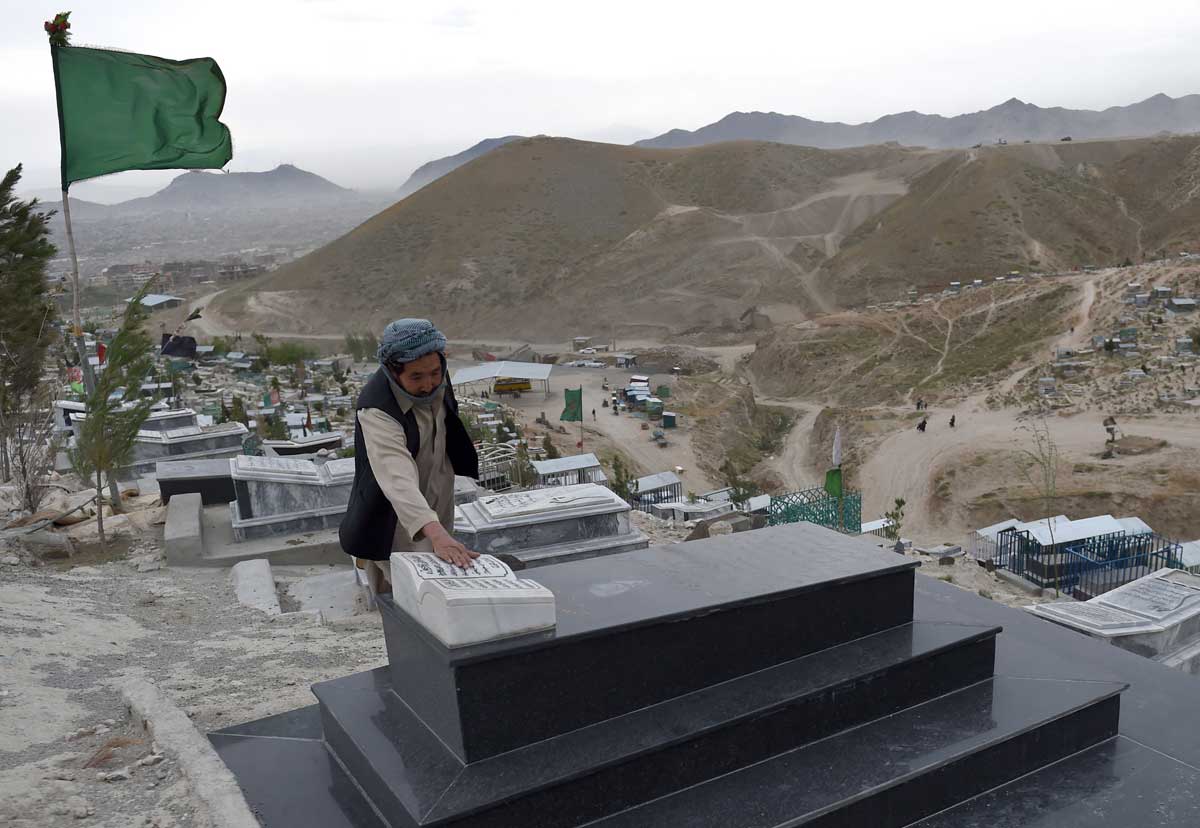 An Afghan man prays at the tomb of a relative, Shuhada cemetery, Kabul © Wakil Kohsar/AFP/Getty Images.