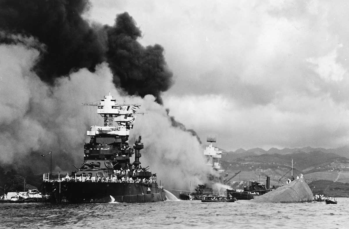 The U.S. Navy battleship USS Maryland (BB-46) alongside the capsized USS Oklahoma (BB-37) at Pearl Harbor, 7 December 1941. The USS West Virginia (BB-48) is burning in the background. US National Archives and Records Administration. 