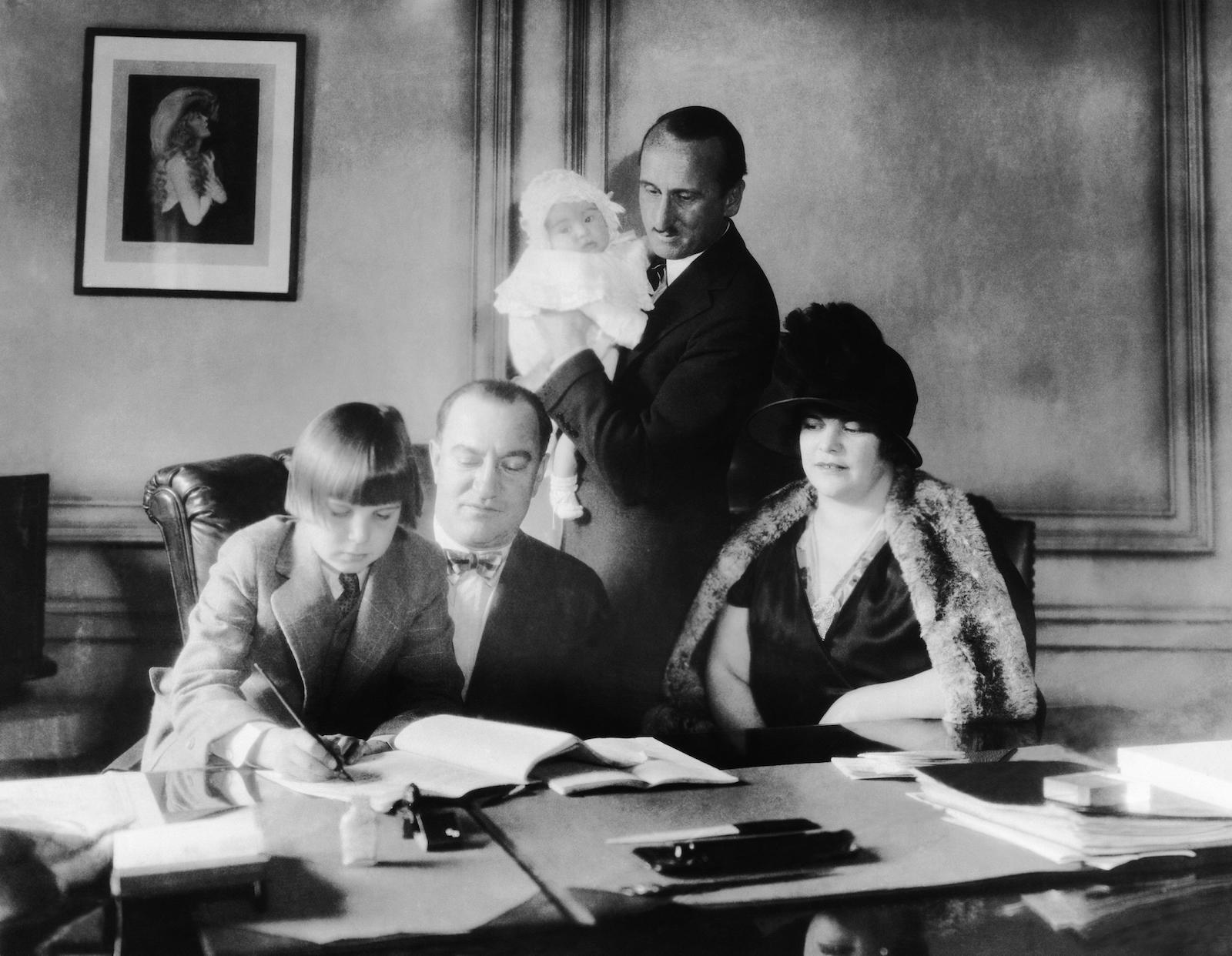 Jackie Coogan signing a contract with MGM vice president Nicholas Schenck, with his parents looking on, 1925. Evertt Collection Inc/Alamy Stock Photo.