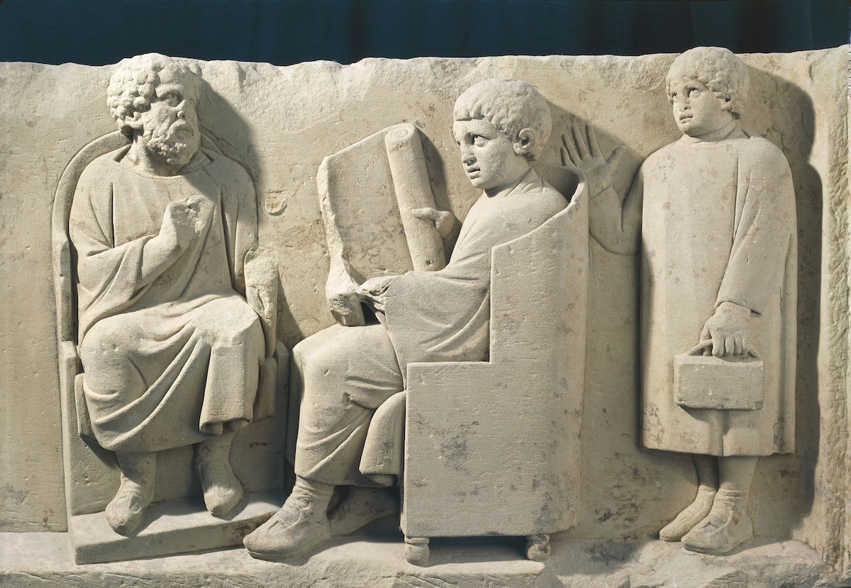 Relief from a burial monument showing a teacher and students, Neumagen, Germany, c.AD 180. G. Dagli Orti/NPL - DeA Picture Library/Bridgeman Images. Relief from a burial monument showing a teacher and students, Neumagen, Germany, c.AD 180. G. Dagli Orti/NPL - DeA Picture Library/Bridgeman Images.