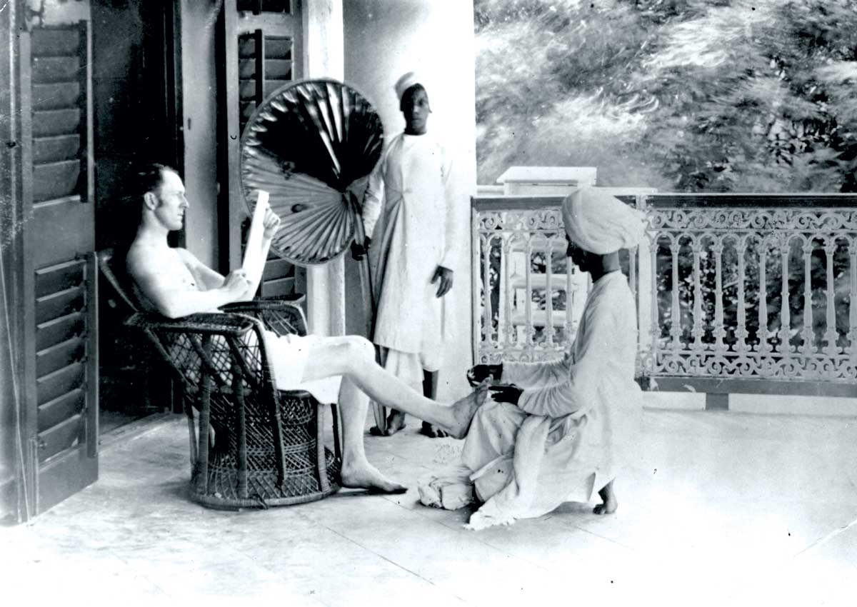 A British officer receiving a pedicure while a punkahwallah stands nearby, c.1900 © Hulton/Getty Images