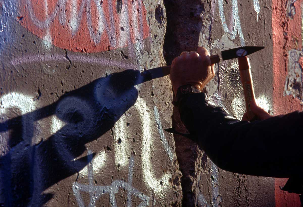 A man from West Berlin uses a hammer and chisel to chip off a piece of the Berlin Wall as a souvenir in November 1989. US Military/Wiki Commons.