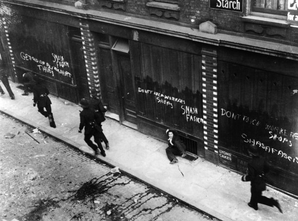 Demonstrators are chased by police past East End shops daubed with antifascist and Communist slogans, October 4th, 1936. Photo / Getty