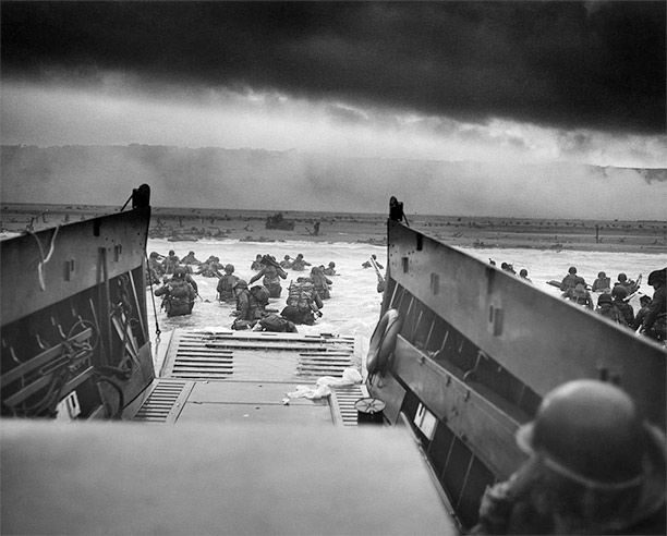 Into the Jaws of Death by Robert F. Sargent. Assault craft land one of the first waves at Omaha Beach. The U.S. Coast Guard caption identifies the unit as Company E, 16th Infantry, 1st Infantry Division.