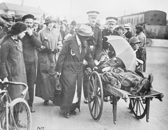 A wounded Belgian officer being assisted by a British Red Cross nurse and a Boy Scout in Folkestone, December 1917. Library of Congress. Public Domain.