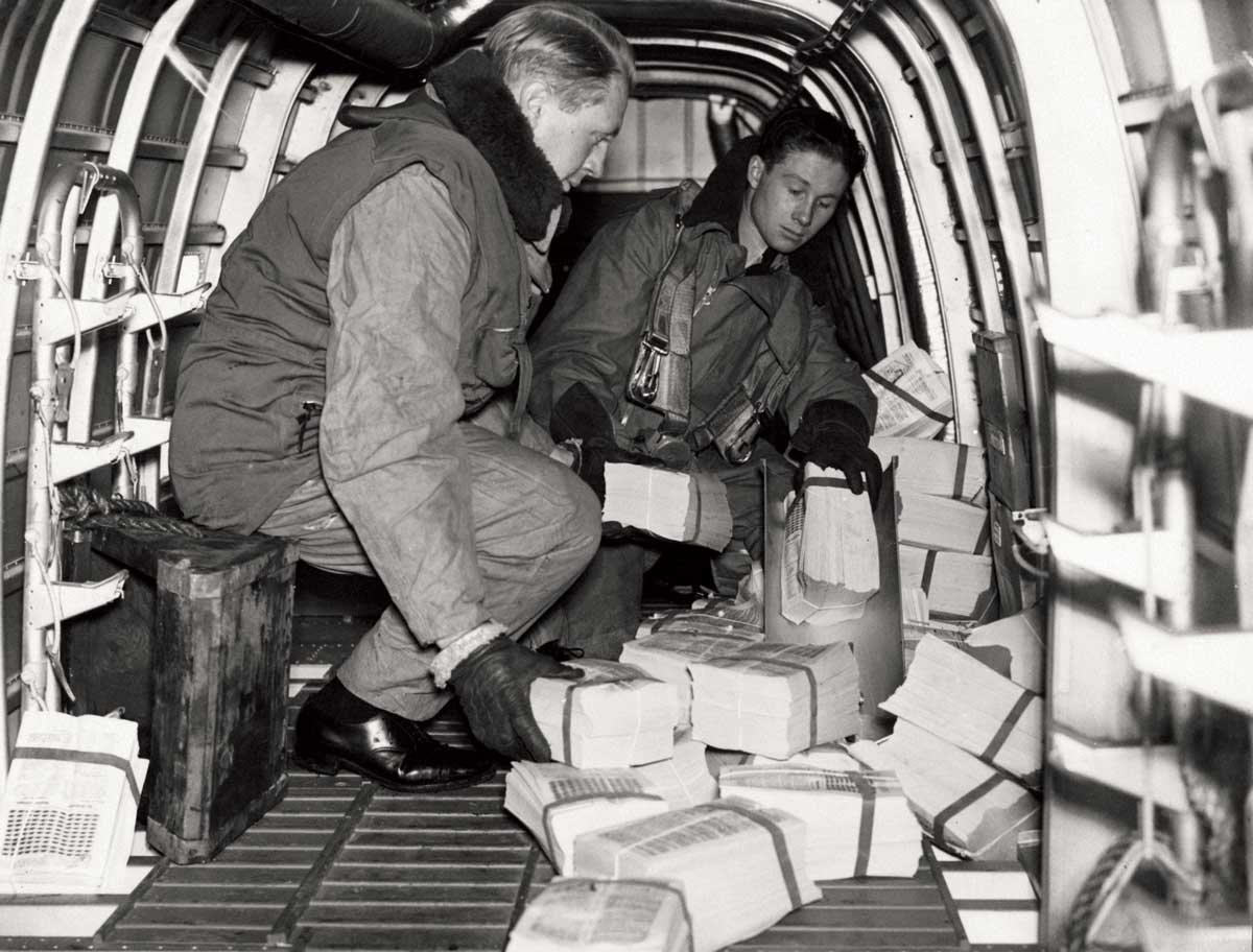 Members of an RAF bomber crew preparing to drop propaganda leaflets over enemy territory, early 1940s.