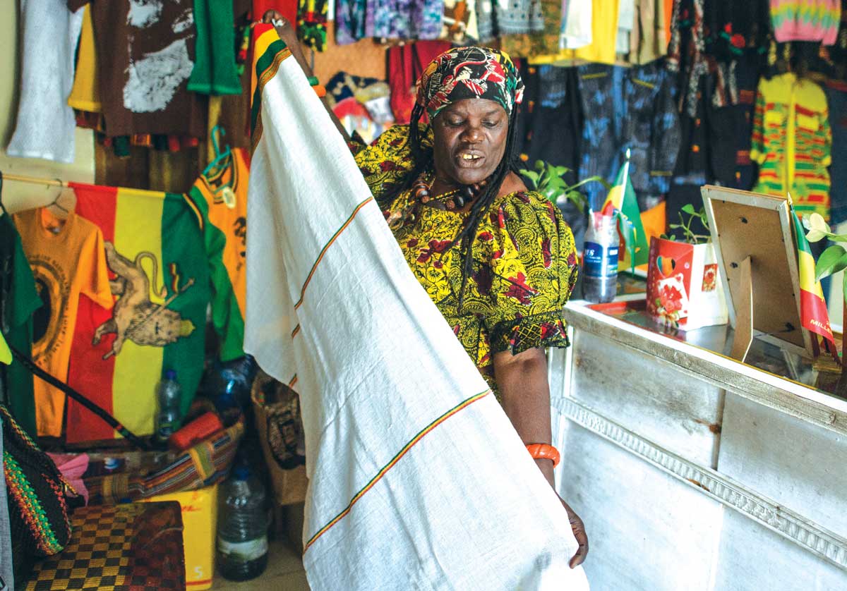 A Rastafari woman shows a traditional Ethiopian cloth in her shop, Shashamane, Ethiopia, 2017.