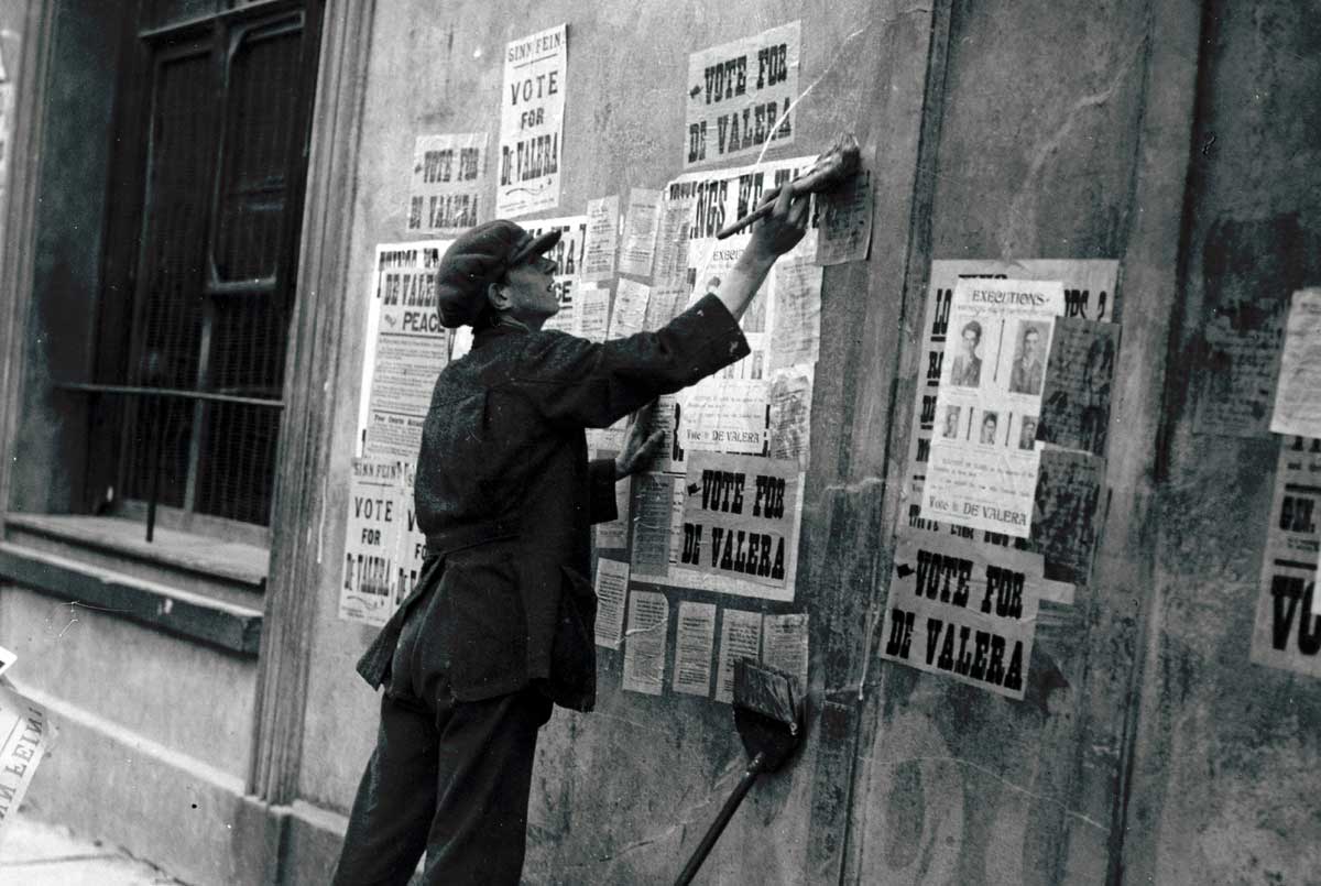 a man pastes over ‘Vote for de Valera’ election posters with arrest notices, Ireland, c.1923 Photo © Topical Press Agency/ Getty Images. Hulton Archive Collection. 