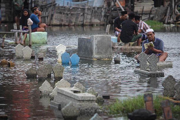 Age-old crisis: a villager prays as rising sea levels submerge graves, Tenggang, Indonesia, June 2014. 