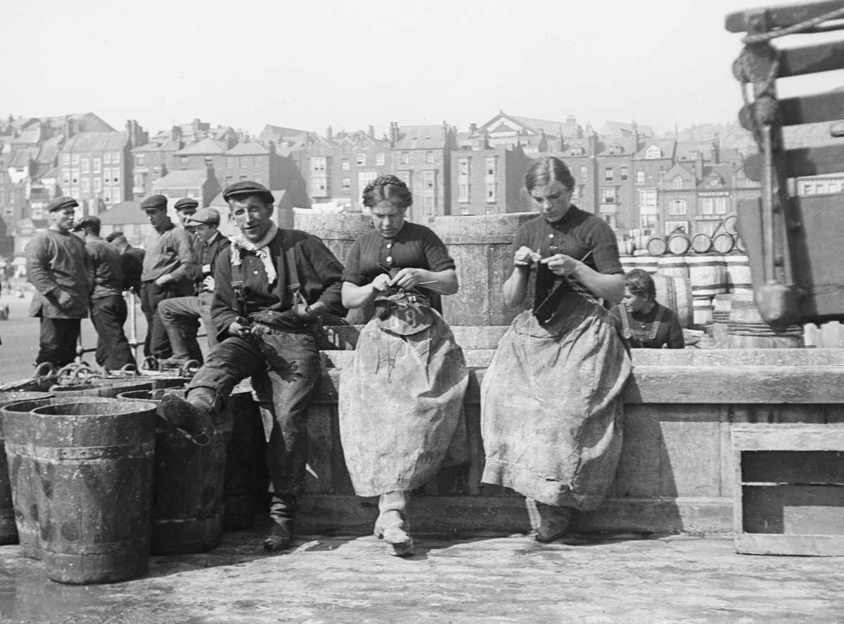 Herring girls knitting at Scarborough harbour, Yorkshire, c. 1910.