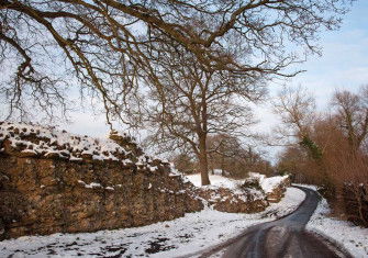 A road runs past the remains of the Roman wall at Silchester.