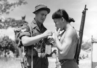 Brothers in arms?: a British soldier lights a cigarette for a Dyak colleague, Malaya, 1950. 