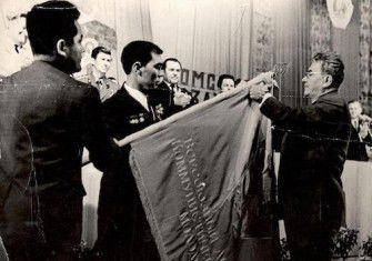Dinmukhamed Kunaev, First Secretary of the Communist Party of Kazakhstan, awarding a Soviet Army unit's battle flag, 1986. EgemenMedia (CC BY-SA 4.0).
