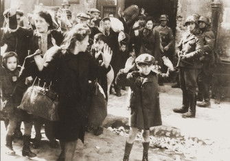 Jews captured during the suppression of the Warsaw Ghetto Uprising are forced from their shelters and marched to the Umschlagplatz for deportation, 1943. United States Holocaust Memorial Museum, courtesy of National Archives and Records Administration, College Park. Public Domain.