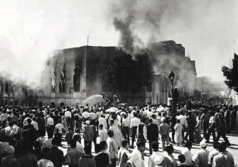 Crowds gather around the burning headquarters of the Muslim Brotherhood in Cairo, 27 October 1954.  It was set on fire after the attempted assassination of Gamal Abdel Nasser. Associated Press/Alamy.