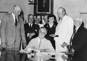 President Roosevelt signs the Social Security Act in the White House, 1935. Harrison is in the white suit. Children's Bureau Centennial (CC BY 2.0)..