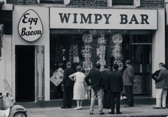Passers-by looking at a modern sculpture in the window of a Wimpy Bar in London, c.1961. Photograph by John ‘Hoppy’ Hopkins. © Estate of John Hopkins.