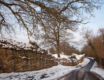 A road runs past the remains of the Roman wall at Silchester.