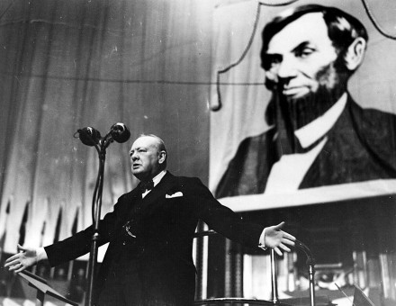 Winston Churchill speaking at the Royal Albert Hall, London, in front of a picture of Abraham Lincoln, 1944. Bridgeman Images.