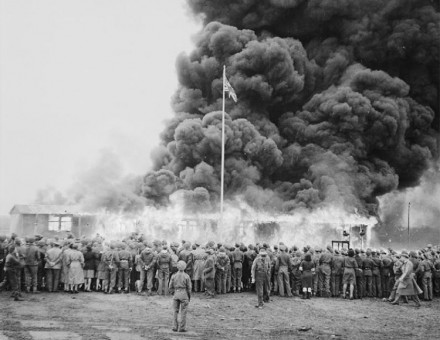 A crowd watches the destruction of the last camp hut.