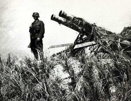 Quiet posting: a soldier in German uniform stands with a captured Dutch gun at Texel, May, 1940.